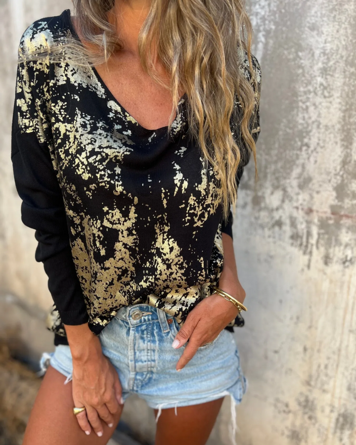 Black and gold relaxed knit top with a V neckline, close up