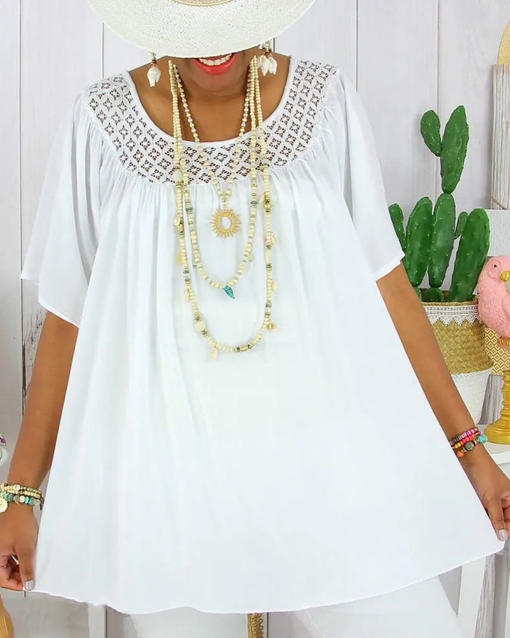 Front view, model wearing a white loose fit summer lace top with a wide brim hat and layered necklaces