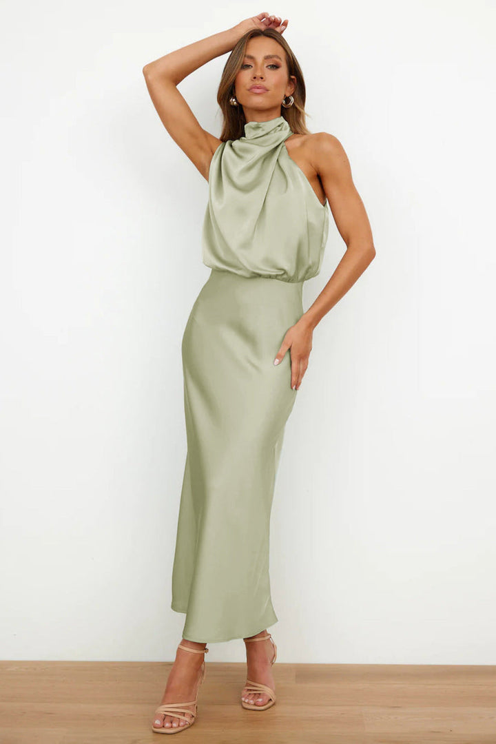 Front view, model wearing a long satin dress in sage green with a draped halter neckline and flowing skirt