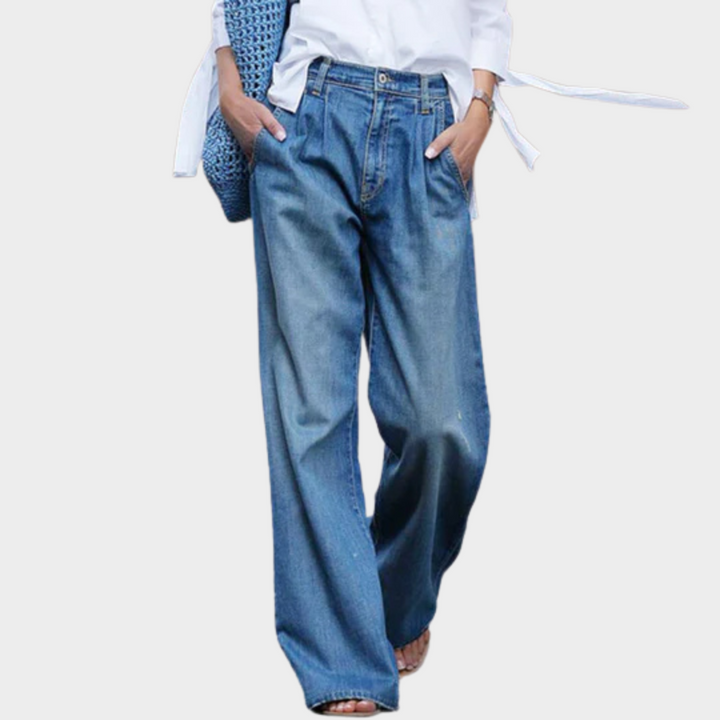 Front view of Natalie jeans worn by model, light wash blue, pleated waist, with hands in pockets, alternate angle