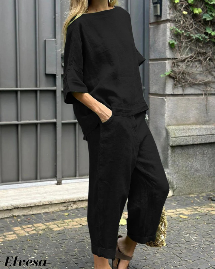 Three quarter view, model wearing a black two piece set with a boat neck top and relaxed fit pants