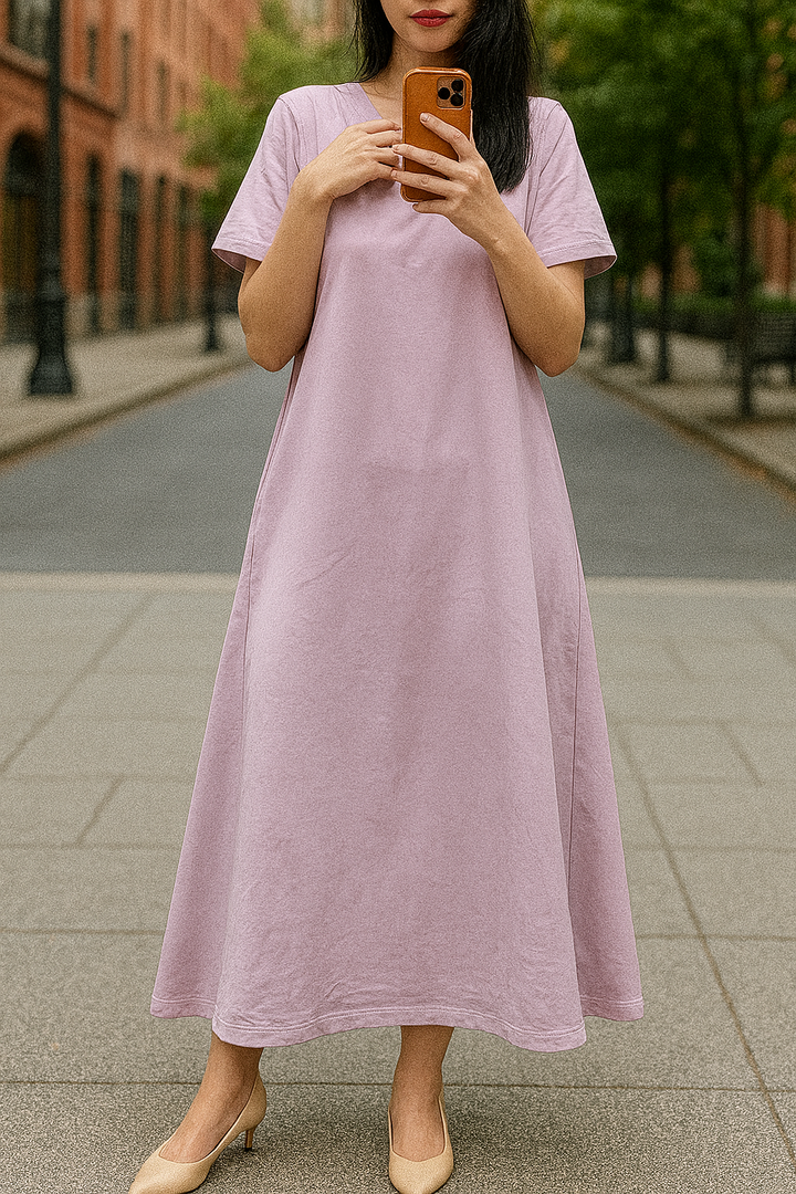 Front view, worn by model, of a flowing maxi dress in a soft lilac colour, holding a phone
