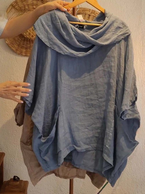 Front view of a light blue linen pocket top with a draped neck and 3/4 sleeves, held by a woman&