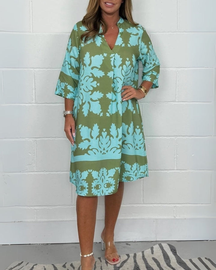 Front view of a woman wearing a green and blue boho V-neck midi dress with 3/4 sleeves