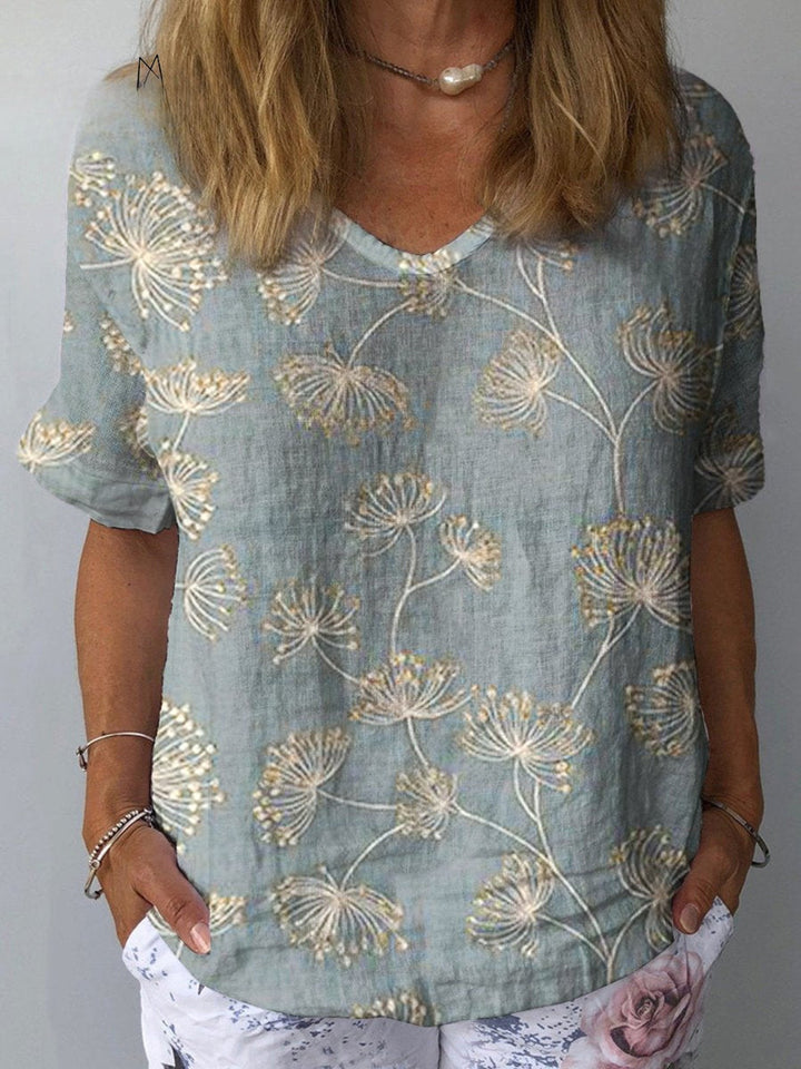 Front view of a woman wearing a relaxed fit dandelion art print cotton linen shirt with hands in pockets