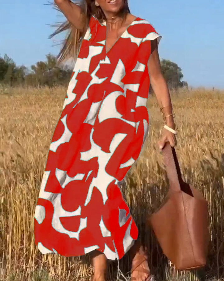 Front view of a model in a red and white abstract print vintage long sundress with a brown leather tote bag