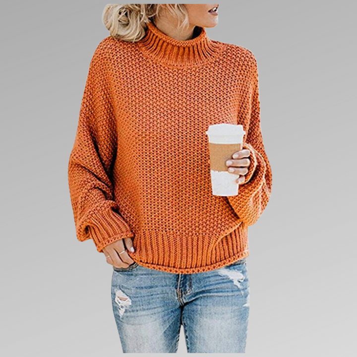 Front view of a model wearing the orange Jovana Airy Touch Knit top with ripped jeans and holding a coffee cup
