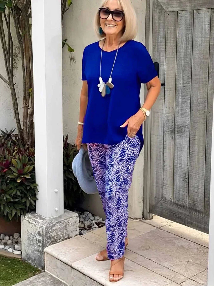 Coastal Grace Set, worn by model, a navy tee and patterned pants, hand in pocket, holding a blue hat