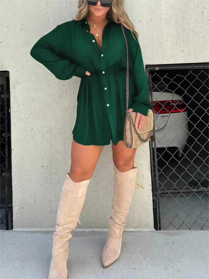 Front view, model wearing a forest green satin romper with a self-tie belt and beige knee high boots
