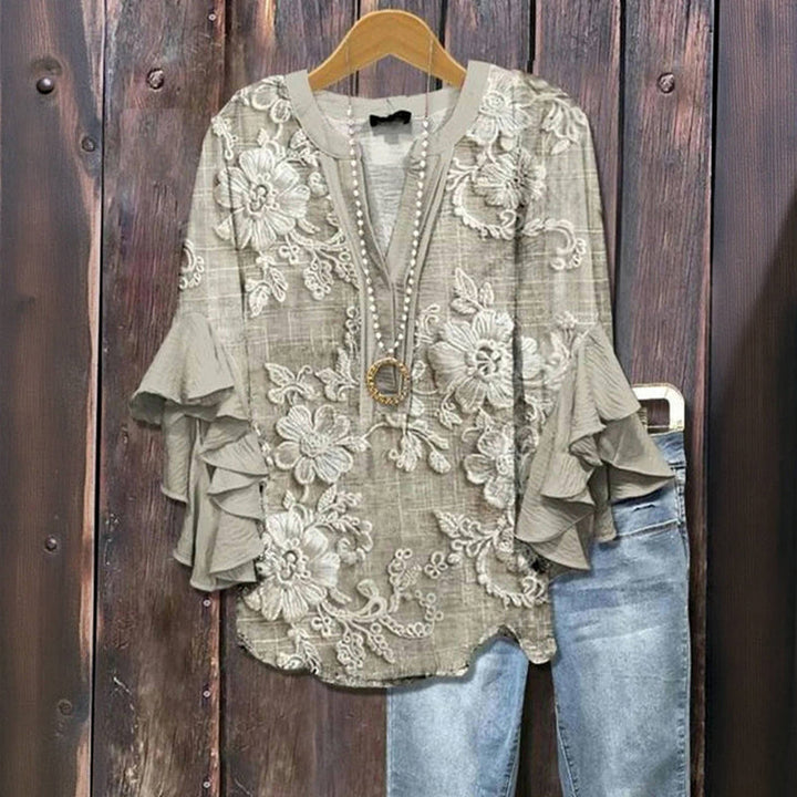 Front view of a grey vintage floral print blouse with ruffle sleeves and a V-neck, displayed with blue jeans