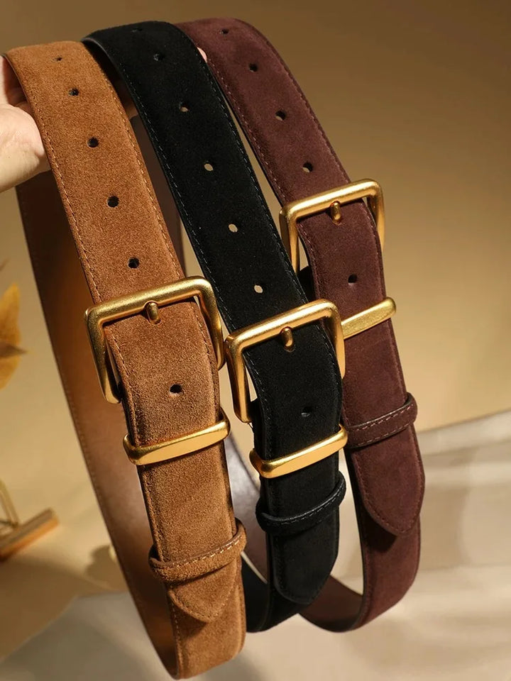 Close up of three vintage suede leather belts in tan, black, and brown with gold buckles