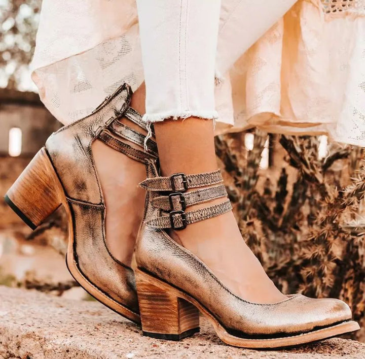 Worn by model, three quarter view of elegant vintage heeled sandals in metallic gold with triple buckled ankle straps
