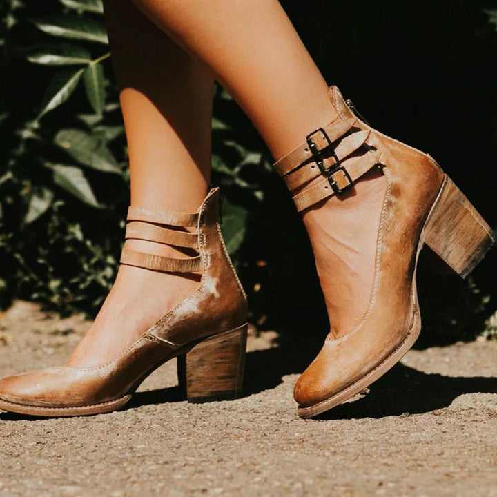 Worn by model, a pair of elegant vintage heeled sandals in a warm caramel hue with block heels