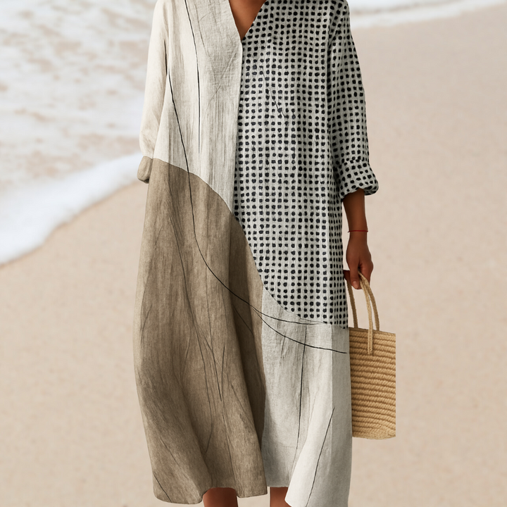 Front view of a model wearing a boho floral print dress with abstract patterns, holding a woven bag on a beach