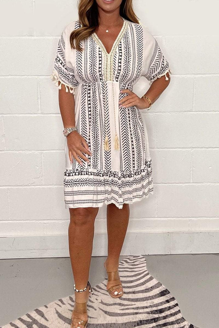 Front view of a woman wearing a white and black striped V-neck summer midi dress with lace trim and tassels