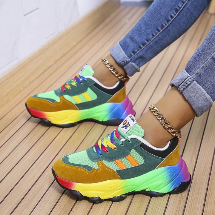 Close up of colourful orthopaedic sneakers with rainbow soles and laces, worn with jeans and anklets