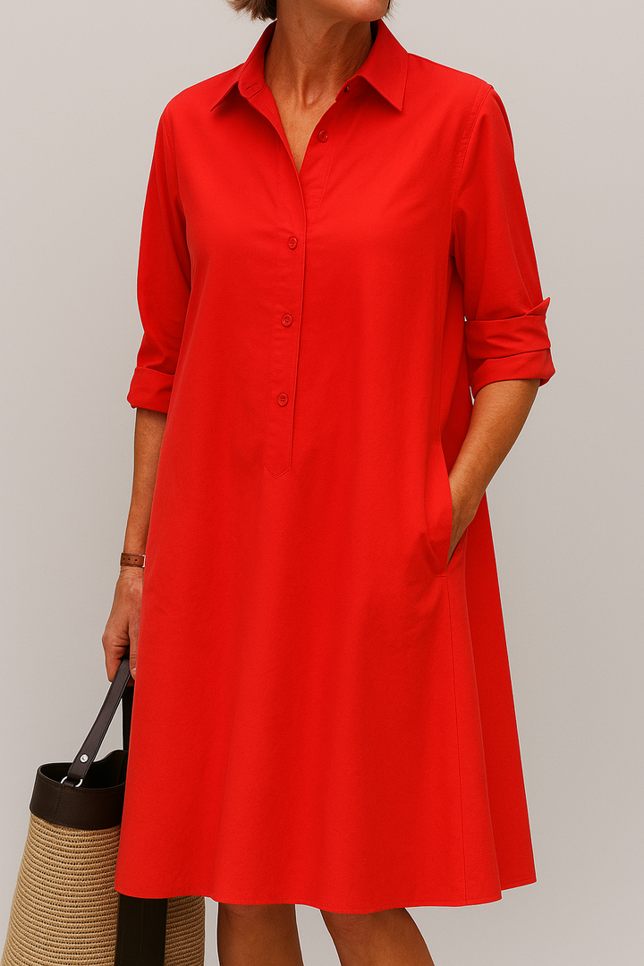 Front view, model wearing a red button-down shirt dress with rolled sleeves, one hand in a pocket