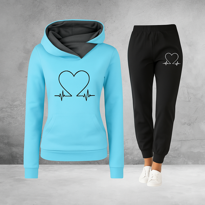 Front view, model wearing a blue Heartbeat Tracksuit sweatshirt and black joggers with a white heart graphic