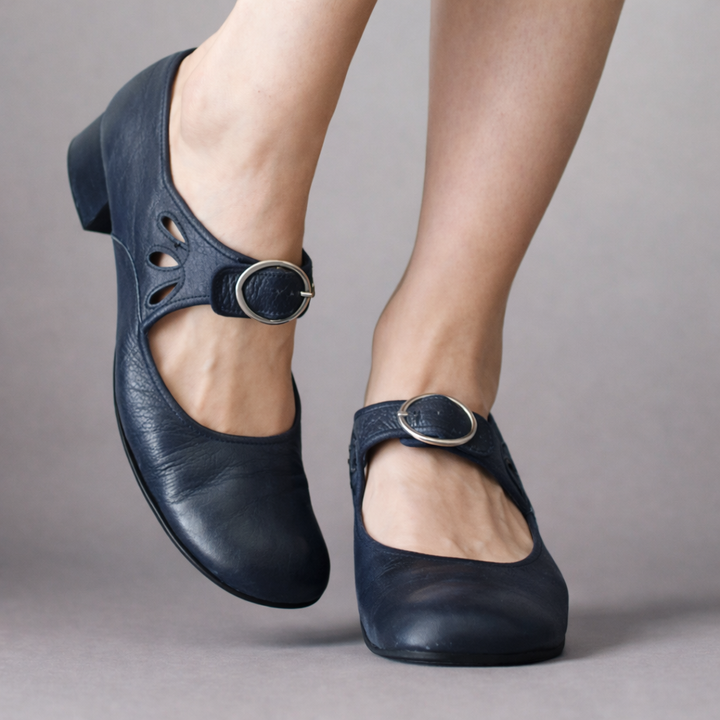 Three quarter view of navy orthopaedic leather wedge sandals worn by model, showing cutouts and buckles