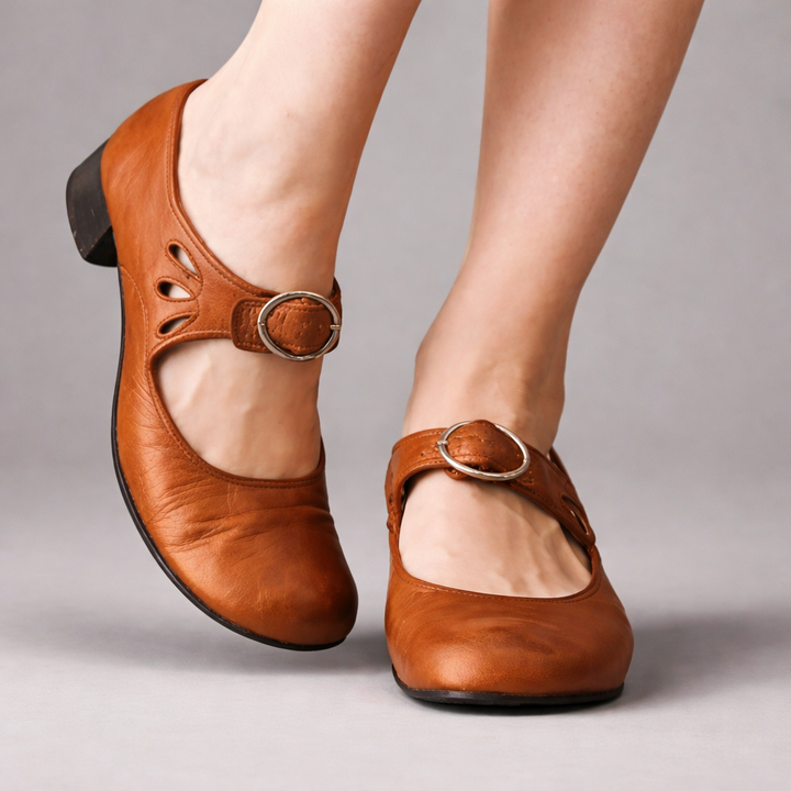 Close up of brown orthopaedic leather wedge sandals worn by model, showing decorative cutouts and buckles