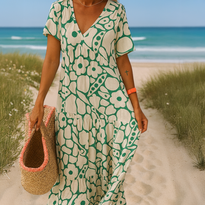 Close up, model in a green and white patterned summer dress with a woven bag on a sandy path