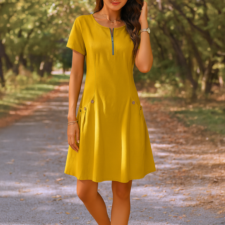Front view of a model wearing the yellow Millie summery dress with zip detail and decorative buttons on pockets