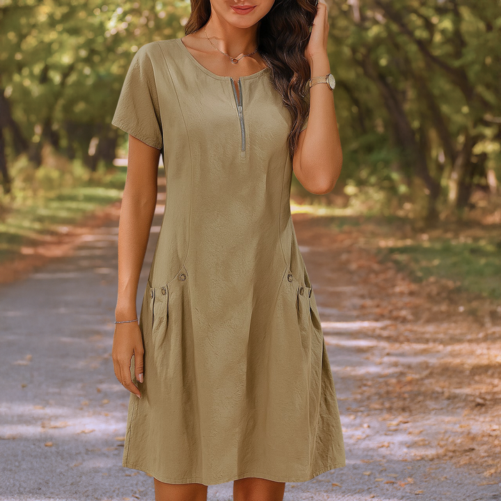 Front view of a model wearing the khaki Millie summery dress with zip detail and decorative buttons on pockets