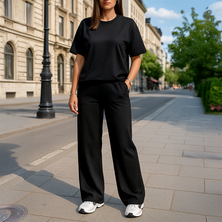 Front view of a woman in a black casual two-piece set with a t-shirt and wide-leg pants, one hand in pocket