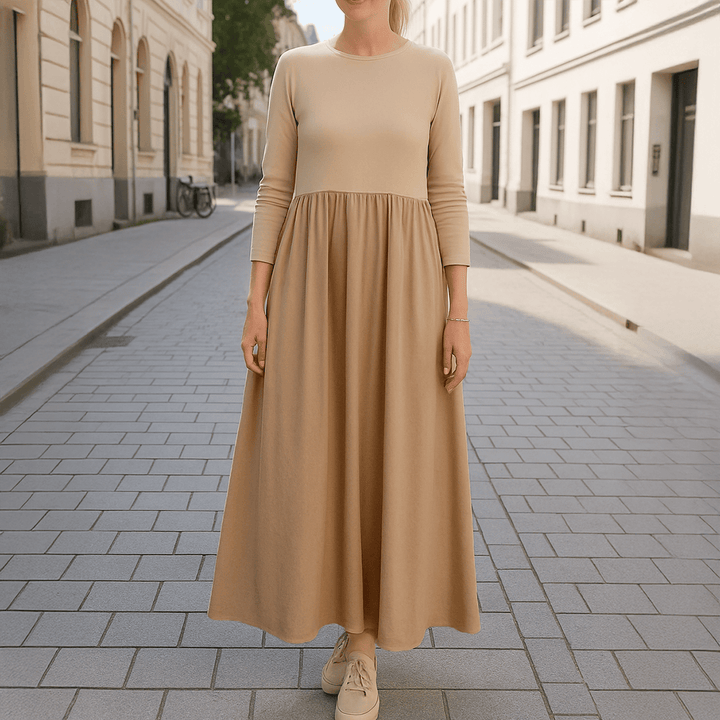 Front view of a woman wearing a beige flowy knitted midi dress with long sleeves in a street setting