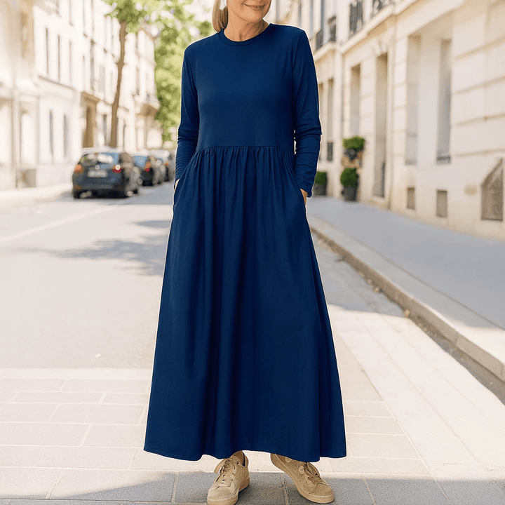 Front view of a woman wearing a navy flowy knitted midi dress with pockets and long sleeves