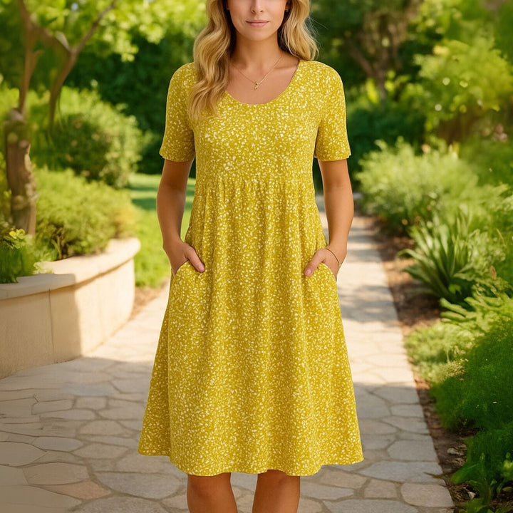 Front view of a model wearing the floral midi shirt dress with hands in pockets on a garden path