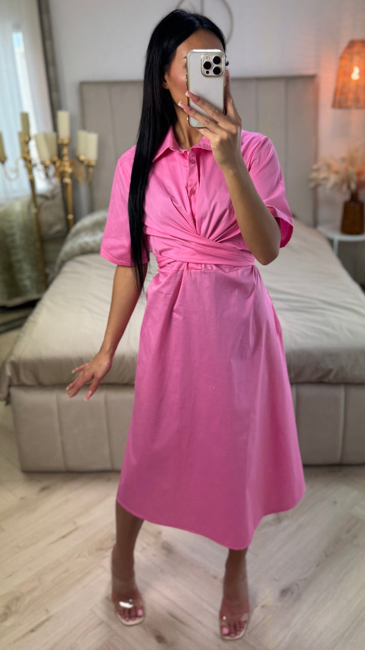 Front view, worn by model, a pink cross tie belt blouse dress in soft cotton blend with a phone covering her face