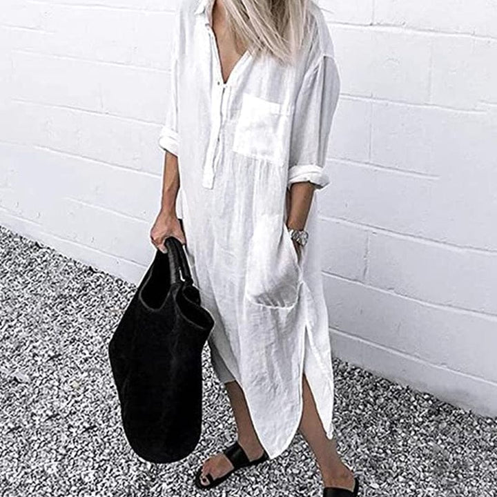 Front view of a model wearing the white elegant solid colour slit shirt dress with a black tote bag and sandals