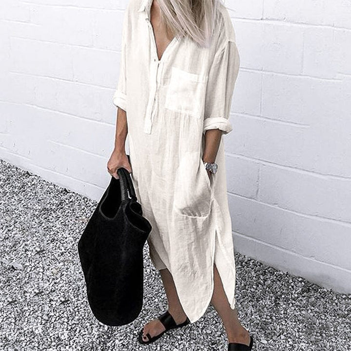 Front view of a model wearing the white elegant solid colour slit shirt dress with a black tote bag