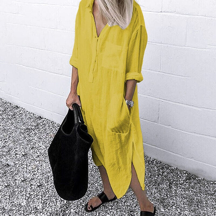 Front view of a model wearing the yellow elegant solid colour slit shirt dress with a black tote bag and sandals