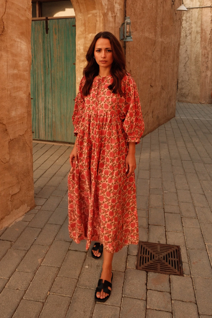 Front view of a model wearing a coral floral maxi dress with lantern sleeves and a relaxed fit