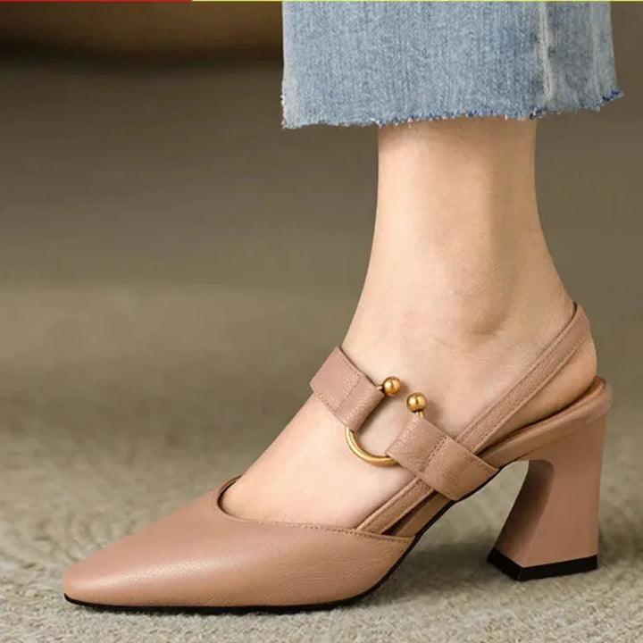 Close up worn by model, nude orthopaedic slingback heels with a gold buckle and supportive block heel