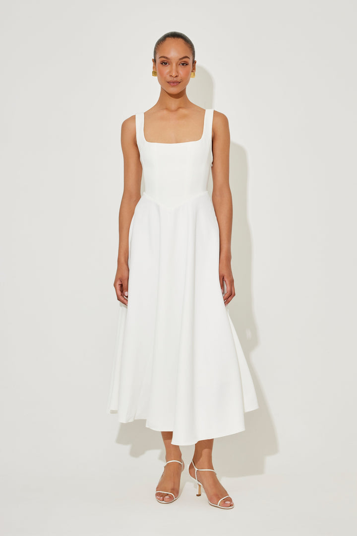 Front view of a model wearing a white timeless flowy midi dress with a square neckline and a high waist