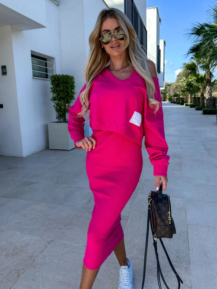 Front view of a model wearing a casual hot pink sweatshirt and dress set with a white square patch on the top