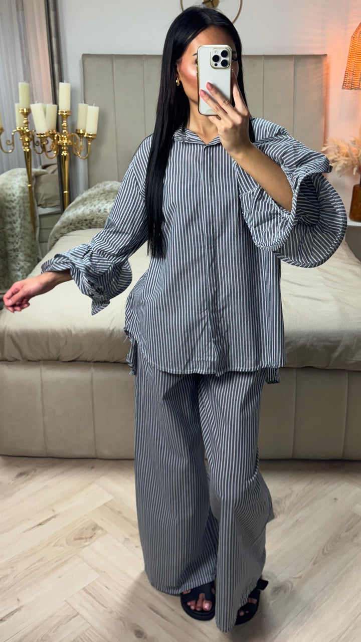 Front view of a model wearing the striped cotton set with ruffle sleeves, holding a phone to her face