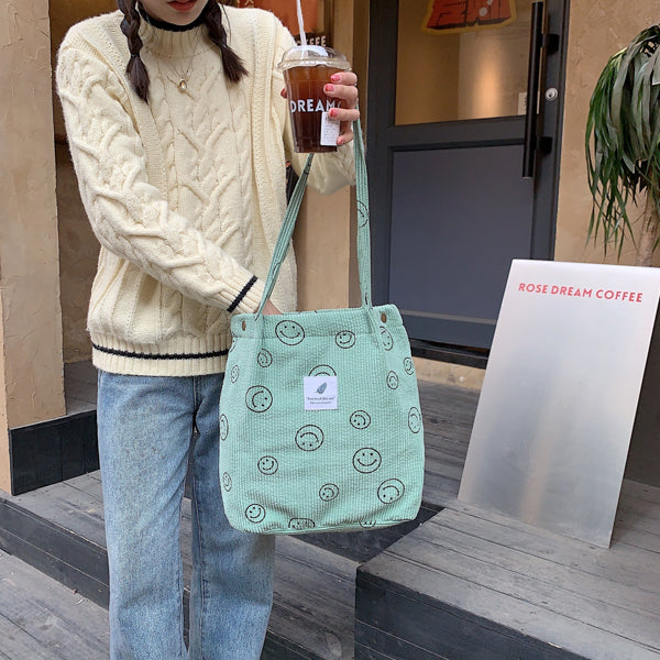 Mint green smiley print corduroy tote bag held with an iced coffee