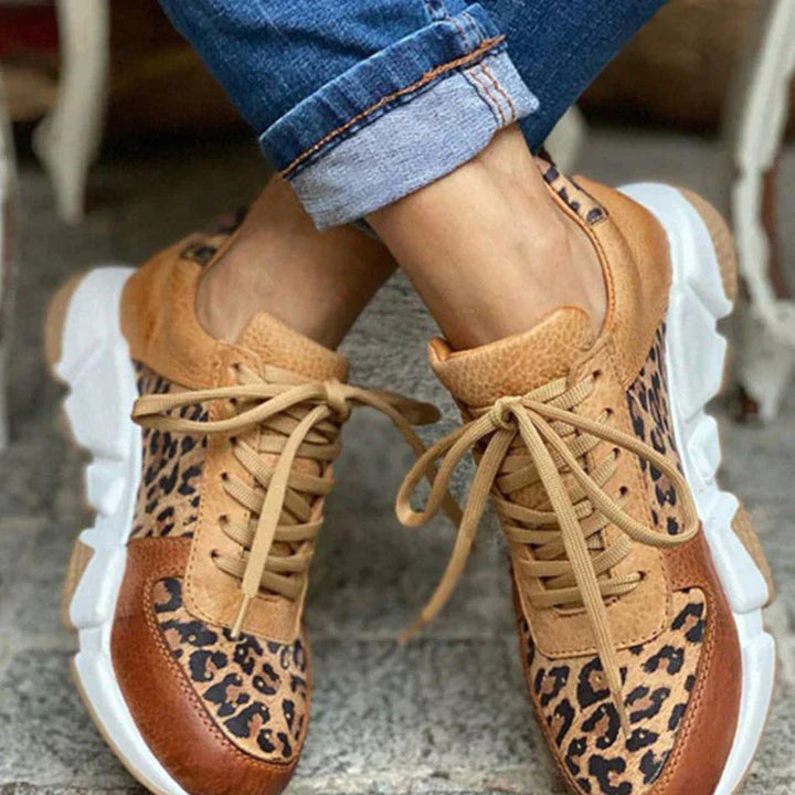 Close up worn by model, leopard print sneakers with tan laces and white soles, cuffed blue jeans
