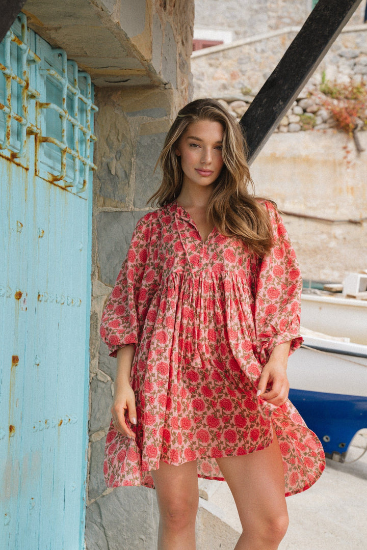 Front view of model wearing a loose boho mini dress with a red floral print and balloon sleeves