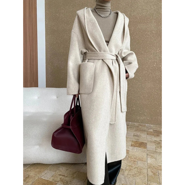 Front view, model wearing a long belted hooded wool blend wrap coat in cream with a burgundy bag
