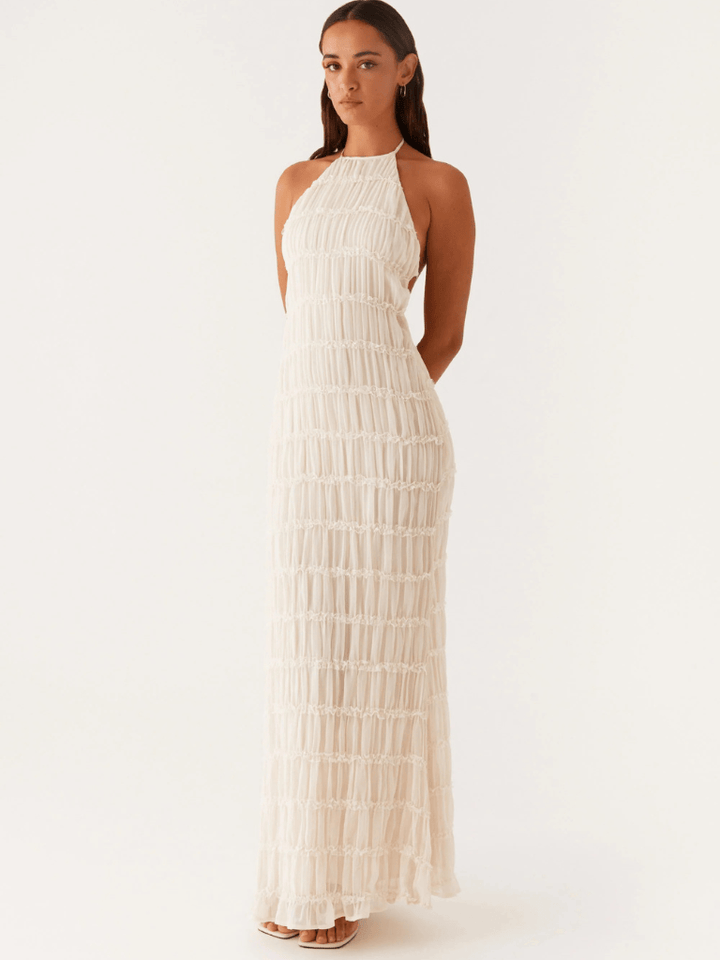Front view of a model in a cream ruched Timeless Evening Dress with a halter neckline and backless design