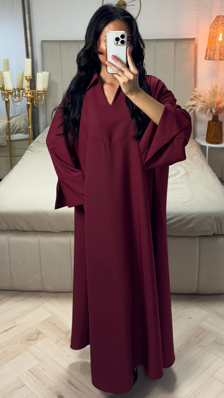 Front view of a model in a maroon cotton abaya, showing the V-neck and split sleeves while holding a phone
