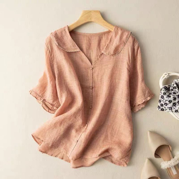 Front view of a pink lightweight linen blouse with a scalloped collar and three quarter sleeves on a hanger