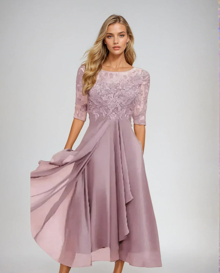 Front view of a model in an elegant chiffon lace long dress with a flowing skirt and three quarter sleeves