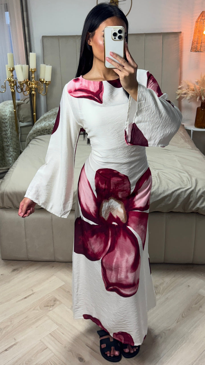 Front view of a model wearing a white floral print maxi dress with large burgundy flowers and elegant bow detail
