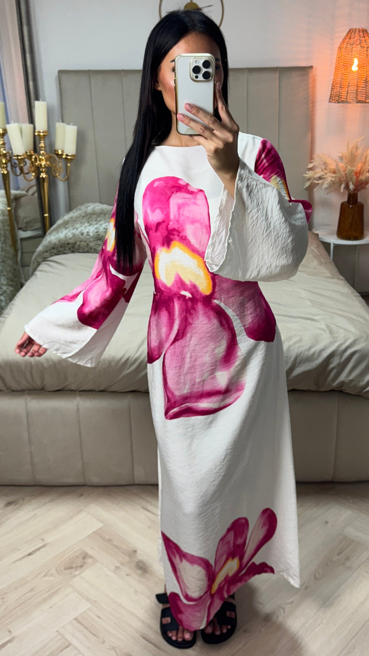 Front view of a model wearing a white floral print maxi dress with large pink and yellow flowers and flared sleeves
